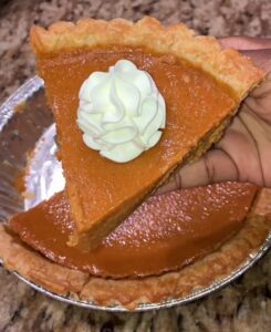A slice of sweet potato pie with whipped cream on top